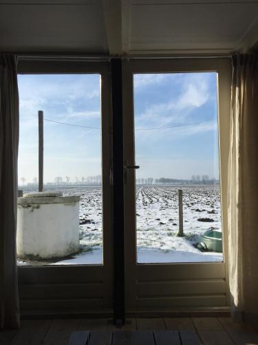 an open door with a view of a snow covered field at Authentic Farmhouse, near beach in Kloosterzande