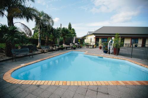 una gran piscina azul en un patio en ASURE Kaimai View Motel, en Katikati