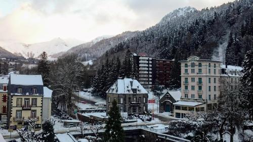 a town covered in snow with mountains in the background at Hôtel de Londres in Le Mont-Dore