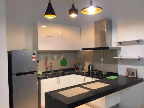 Una cocina con gabinetes blancos y un refrigerador de acero inoxidable. en The Loft Imago Studio Suites, Kota Kinabalu, en Kota Kinabalu