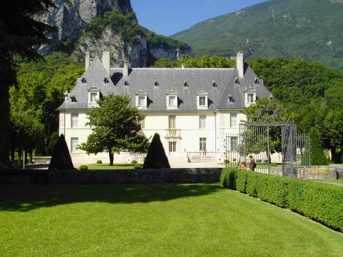 une grande maison blanche avec une pelouse verte en face de celle-ci dans l'établissement La Mare aux oiseaux 1608, à Sassenage