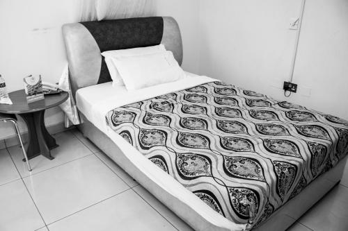 a bed with a black and white comforter and a table at Hotel Jfrigh in Kampala