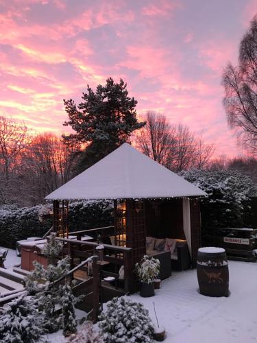 a gazebo covered in snow with a sunset at Ardlogie Guest House in Aviemore