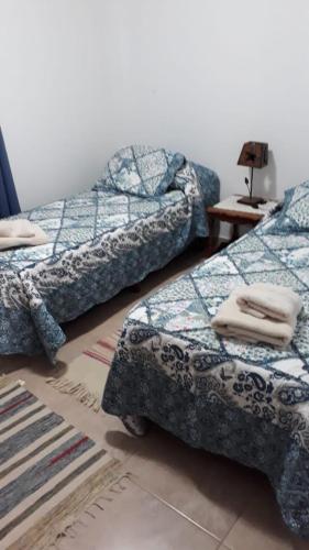 a room with two beds and a table with a lamp at Peggy´s House in Puerto San Julián