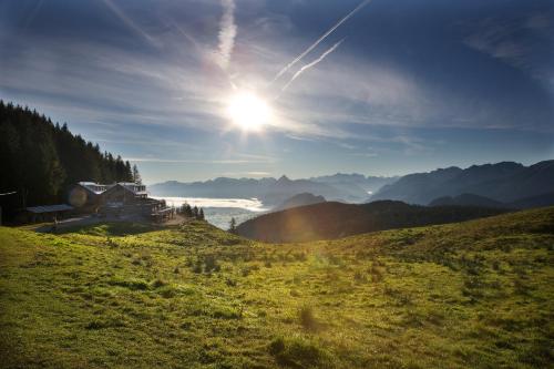 a house on a hill with the sun in the sky at BöckLodges in Nesselwang