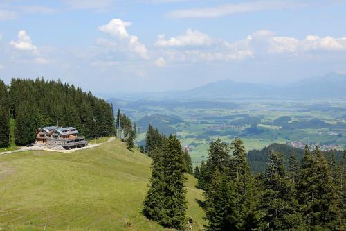 a house on top of a grassy hill with trees at BöckLodges in Nesselwang