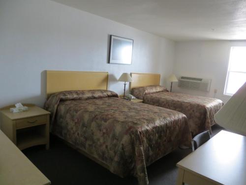 um quarto de hotel com duas camas e uma mesa em Lazy J Motel em Claresholm