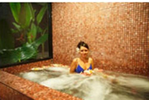 a woman in a bath tub in a bathroom at Hanamitsu Hotel & Spa in Garapan