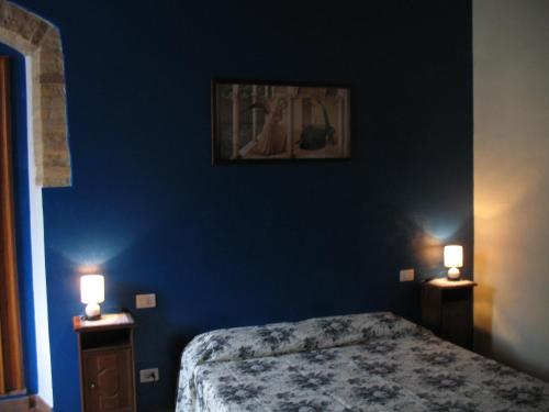 a bedroom with a blue wall with a bed and two lights at Locazione Turistica Totti in San Gimignano