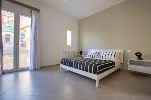 a white bedroom with a bed and a large window at Le Cupole Suites & Apartments in Trapani