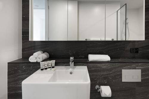 a bathroom with a white sink and a mirror at Modern, new 2 bed in the heart of Darling Harbour in Sydney