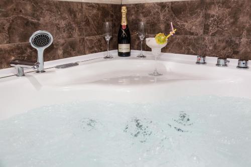 a bath tub with two glasses and a bottle of wine at Iberia Palace Hotel in Zugdidi