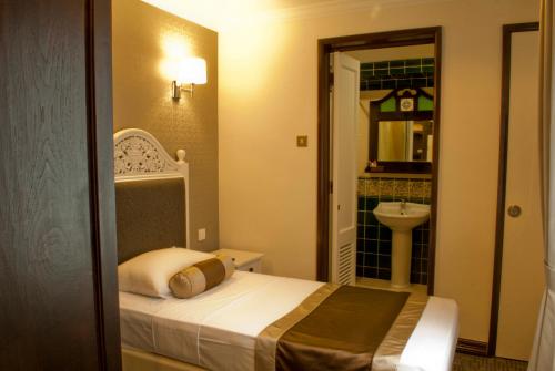 um pequeno quarto com uma cama e um lavatório em The Inn at Temple Street em Singapura