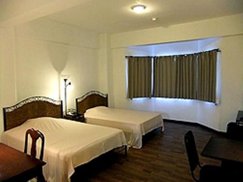 a hotel room with two beds and a desk at Himawari Hotel in Garapan