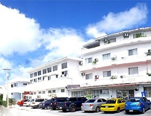 ガラパンにあるヒマワリ ホテルの大きな白い建物とその前に駐車された車