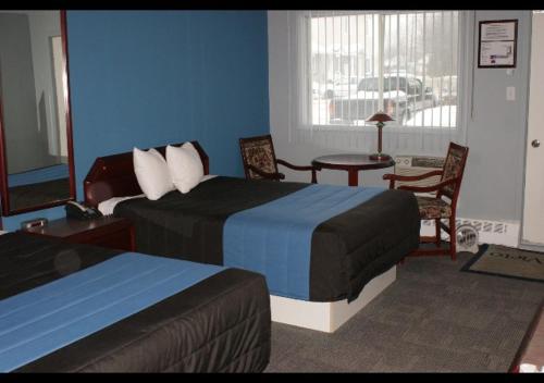 a hotel room with two beds and a table and chairs at Motel Le Victo in Victoriaville