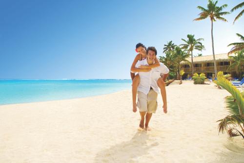 a man carrying a man on a beach at Sanctuary Rarotonga on the Beach (Adults Only) in Rarotonga