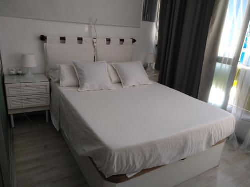 łóżko z białymi prześcieradłami i poduszkami w sypialni w obiekcie Moderno apartamento Torremolinos centro w mieście Torremolinos