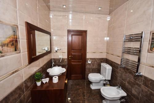 a bathroom with two toilets and a sink and a mirror at Iberia Palace Hotel in Zugdidi