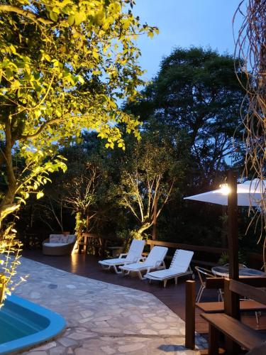 a group of chairs and an umbrella and a pool at Pousada Rosa in Praia do Rosa