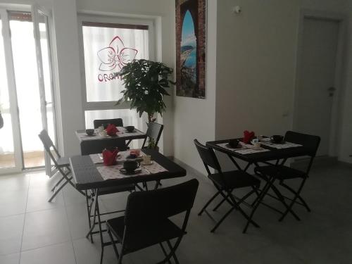 una sala da pranzo con due tavoli con sedie e una pianta di B&B Orchidea a Salerno