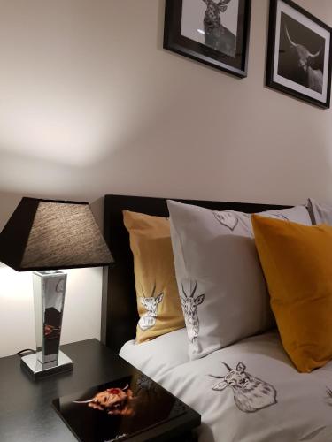 a bed with yellow pillows and a table with a lamp at Smart & Cozy Holiday Apartment in the city centre in Inverness