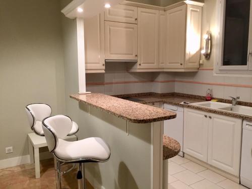 une cuisine avec des placards et des tabourets blancs dans l'établissement NICE 115 BY THE SEA, à Nice