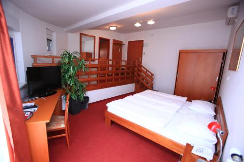 a bedroom with a bed and a desk and a television at Hotel Orion in Ivanec
