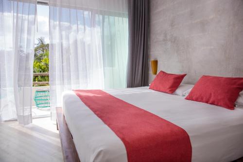 a bedroom with a large bed with red pillows and a window at Villas H2O in Tulum