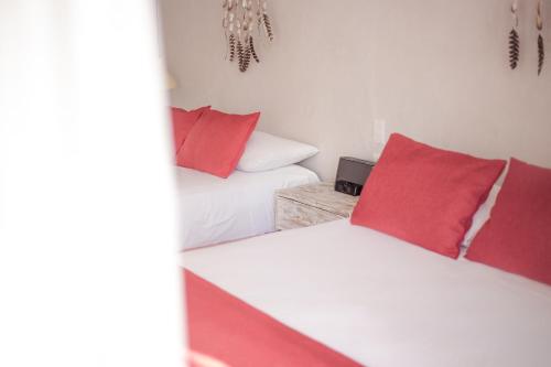 two beds with red pillows in a room at Villas H2O in Tulum