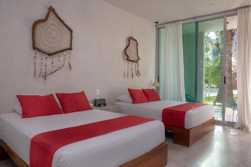 two beds in a hotel room with red pillows at Villas H2O in Tulum