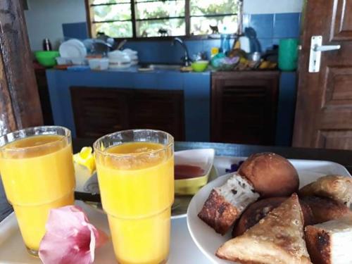 a plate of food with two glasses of orange juice at Mango Lodge MSAMBWENI in Kisimachande