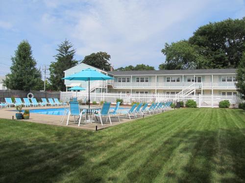 a building with chairs and an umbrella and a pool at The Escape Inn in South Yarmouth
