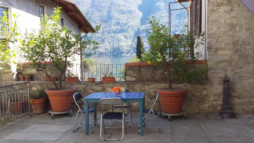 uma mesa azul e cadeiras numa varanda com plantas em Casa Soldino em Laglio