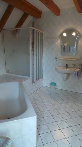 a white bathroom with a tub and a sink at Hotel garni zur Linde in Lauf