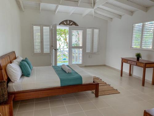 a bedroom with a bed with white walls and windows at El Mosquito Boutique Hotel Playa Bonita in Las Terrenas