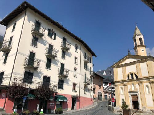 a large white building next to a church at Residence Milcar in Chiesa in Valmalenco