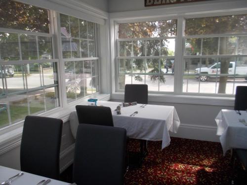 uma sala de jantar com mesa, cadeiras e janelas em Seaway Manor B&B em Gananoque