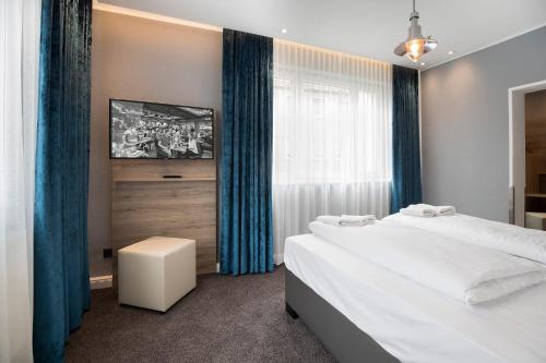 a bedroom with two beds and a tv on the wall at Hotel dasPaul in Nürnberg