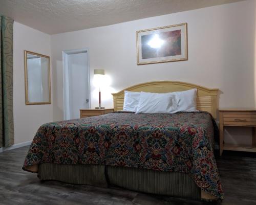 a bedroom with a bed with a blanket and a lamp at Travelers Inn - Clearwater in Clearwater