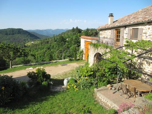 une maison avec une table et un banc dans une cour dans l'établissement Le Petit Rias Gîte Soleil, à Saint Maurice en Chalencon