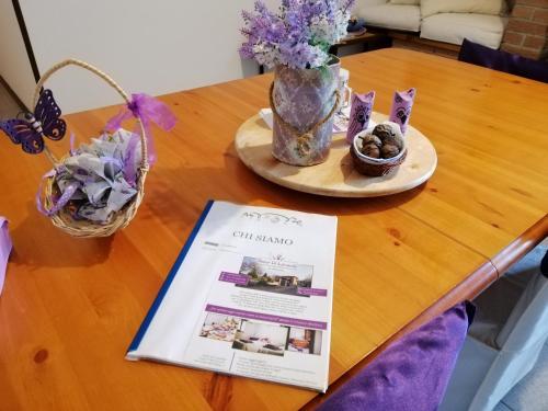a table with a magazine and flowers and a vase at Amor di Lavanda in Cingoli
