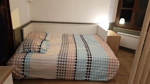 małą sypialnię z łóżkiem z kołdrą w obiekcie 10 Rue du Bourg Neuf w mieście Bruyères-le-Châtel