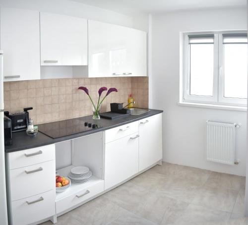 a kitchen with white cabinets and a sink and a window at Davcom Studio in Făgăraş
