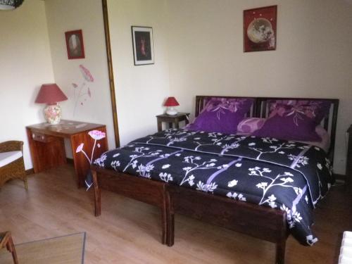 a bedroom with a bed with purple sheets and a table at Chambre d'hôtes La Haie Fleurie in Chevillard