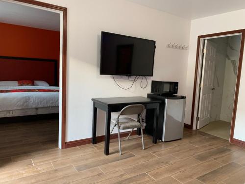 norwalk inn & suites في نورووك: غرفة نوم مع مكتب مع تلفزيون وسرير