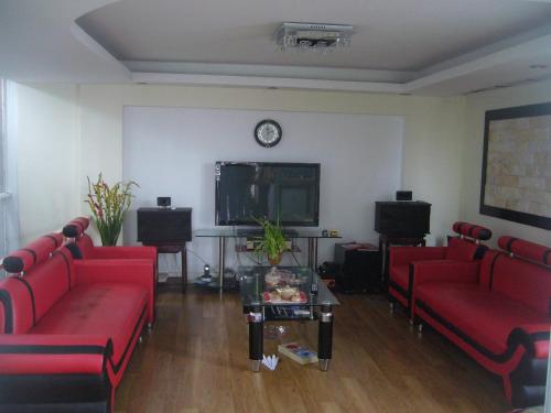 a living room with red couches and a tv at Green Homestay in Hanoi