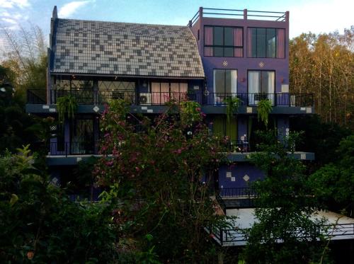 a purple house with a balcony and trees at Pupiang po Da Arte Resort in Dan Sai