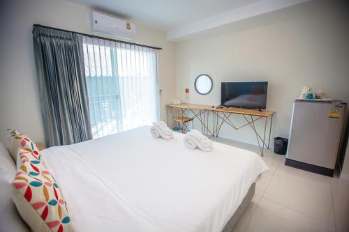 a bedroom with a white bed and a television at iRabbit Hotel in Prachin Buri
