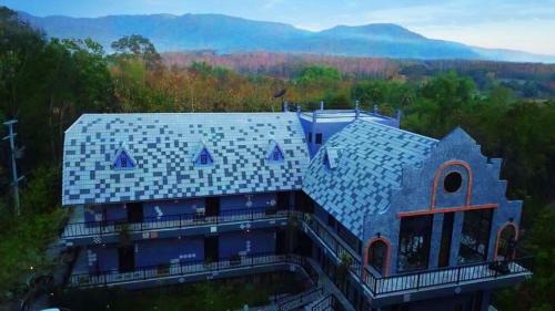 a house with a blue roof with mountains in the background at Pupiang po Da Arte Resort in Dan Sai